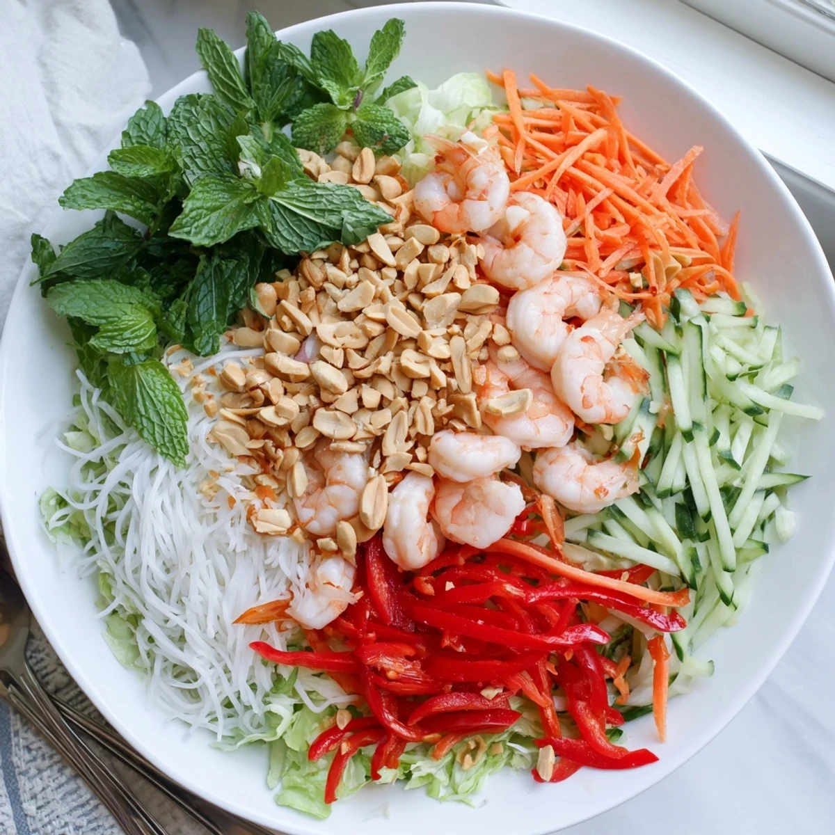 Fresh Spring Roll Salad in bowl topped with tender shrimp, vermicelli noodles, roasted peanuts, and zesty ginger dressing.