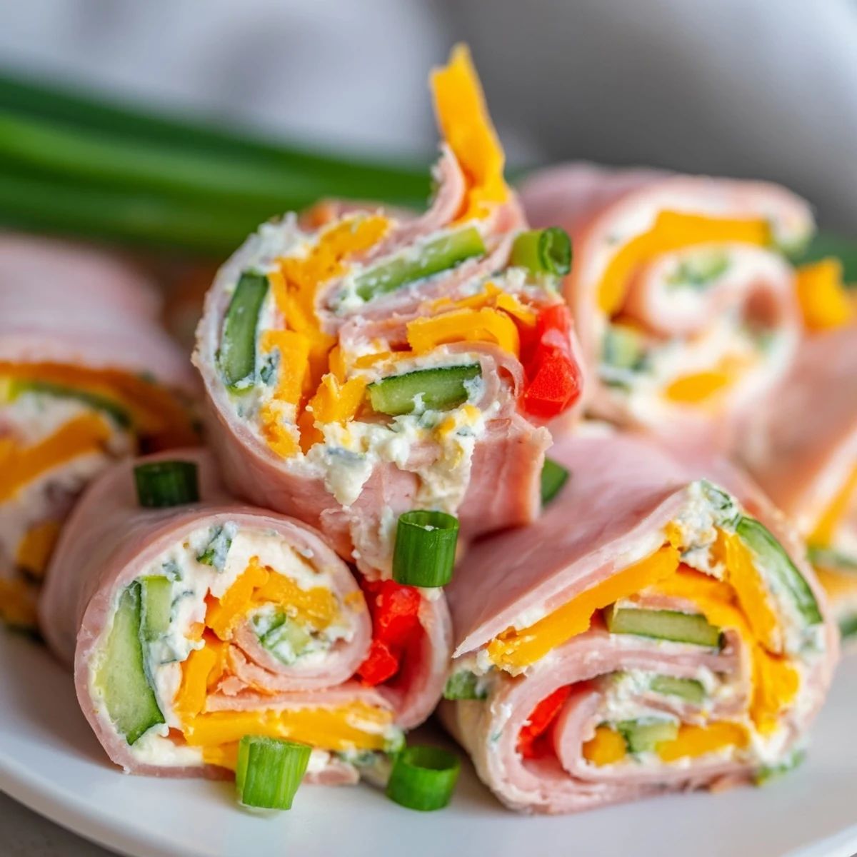 Golden keto ham roll ups stuffed with creamy cheese spread and crisp colorful vegetable strips