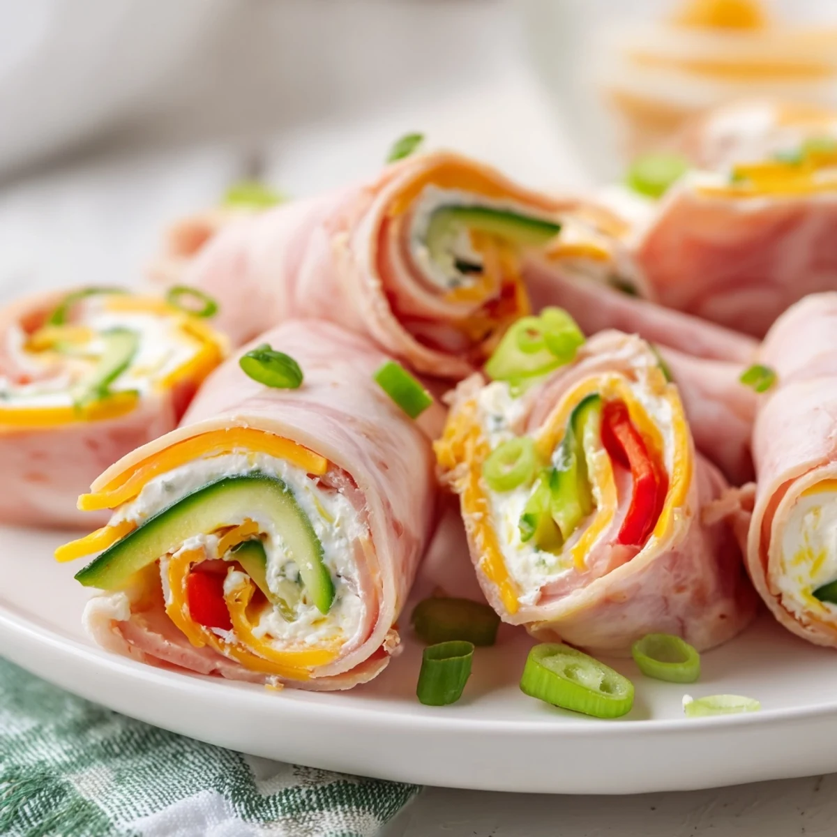 Close up of savory keto ham roll ups sliced to reveal cheddar cream cheese and julienned vegetables