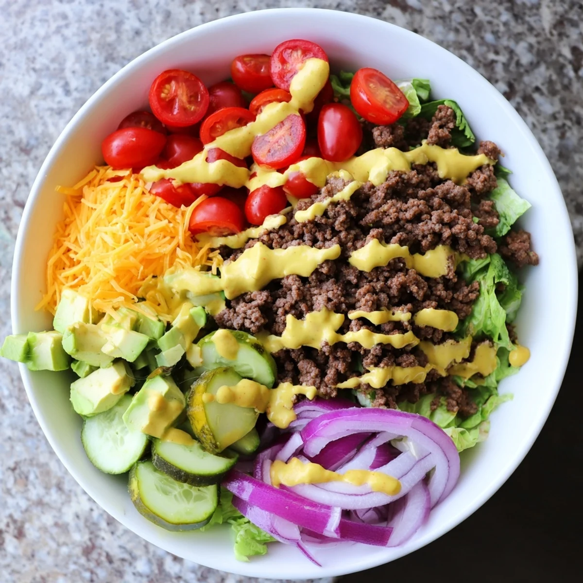 Deconstructed burger bowls with seasoned ground beef, fresh vegetables, cheddar, and creamy special sauce