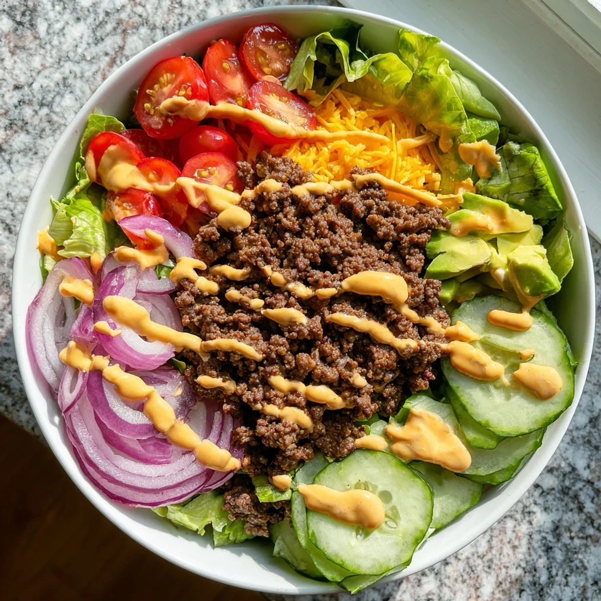 Gluten-free burger bowls piled with spiced ground beef, avocado, cheese, and drizzled dressing