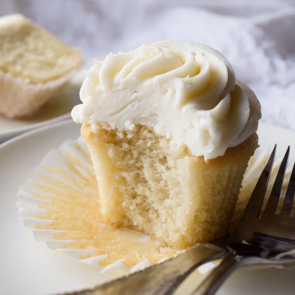 Freshly baked vanilla cupcakes piped with smooth buttercream on a rustic wooden board
