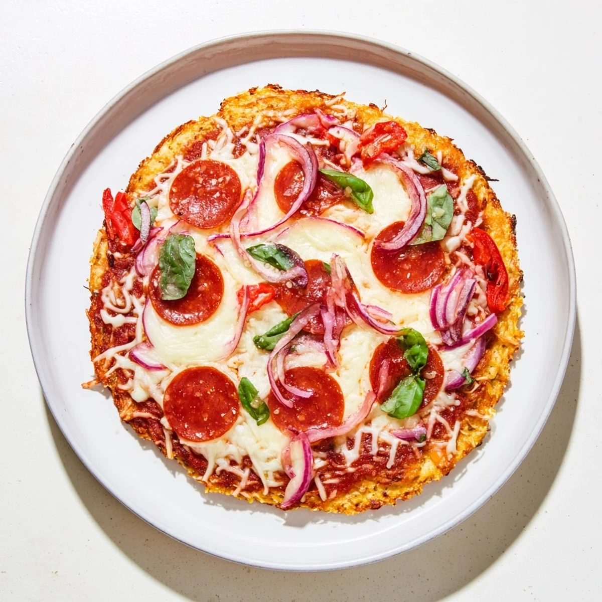 Golden crispy chicken crust pizza loaded with melted mozzarella and pepperoni on a white plate