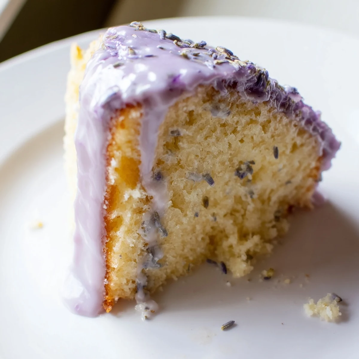 Soft lavender cake topped with sweet citrus icing on white plate
