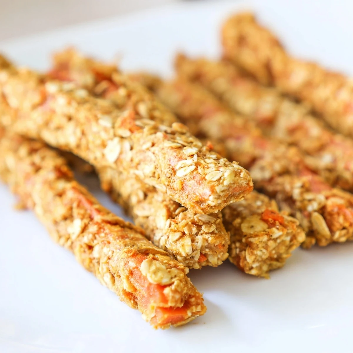Golden brown apple and carrot dog chew sticks arranged on parchment paper for homemade treats