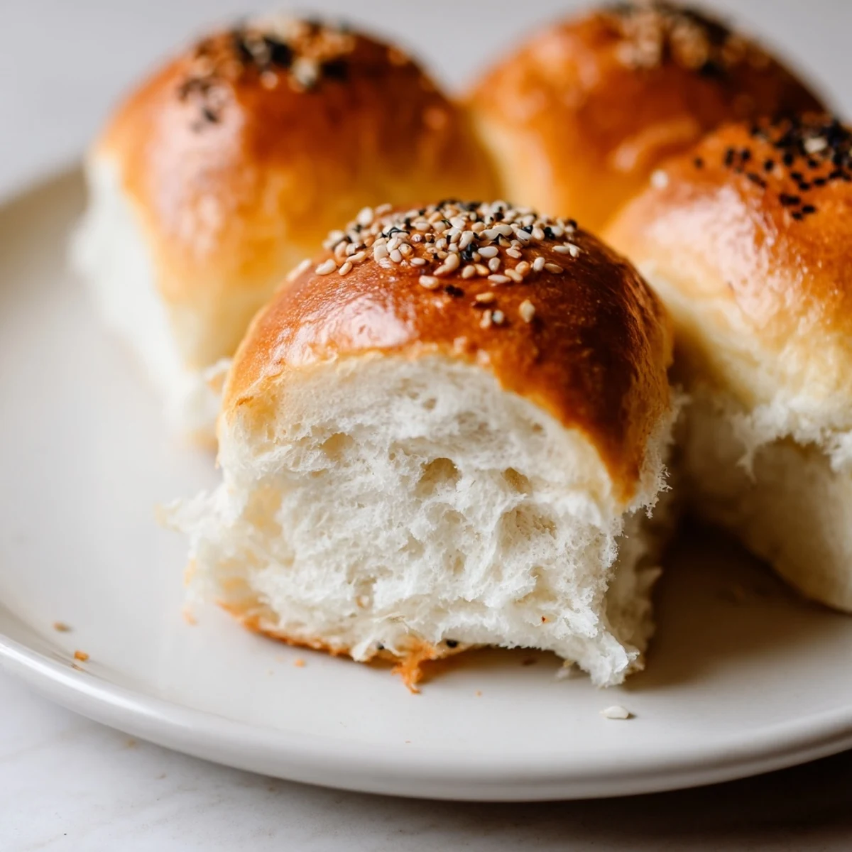 Golden sourdough discard hot dog buns fresh from the oven with sesame seed topping