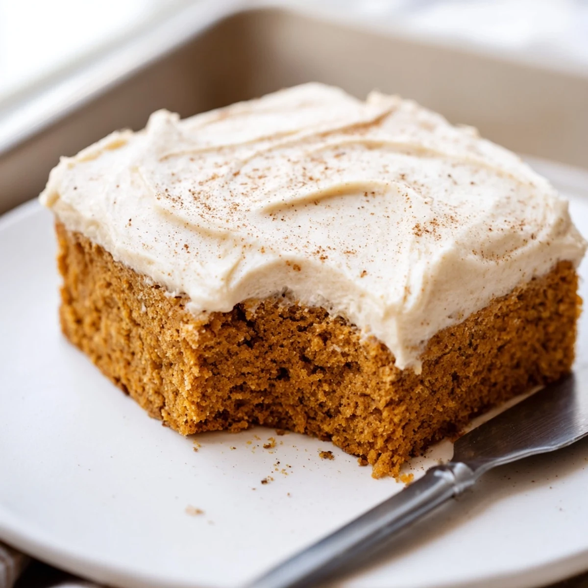 Warmly spiced pumpkin bars with cream cheese frosting dusted with cinnamon on top