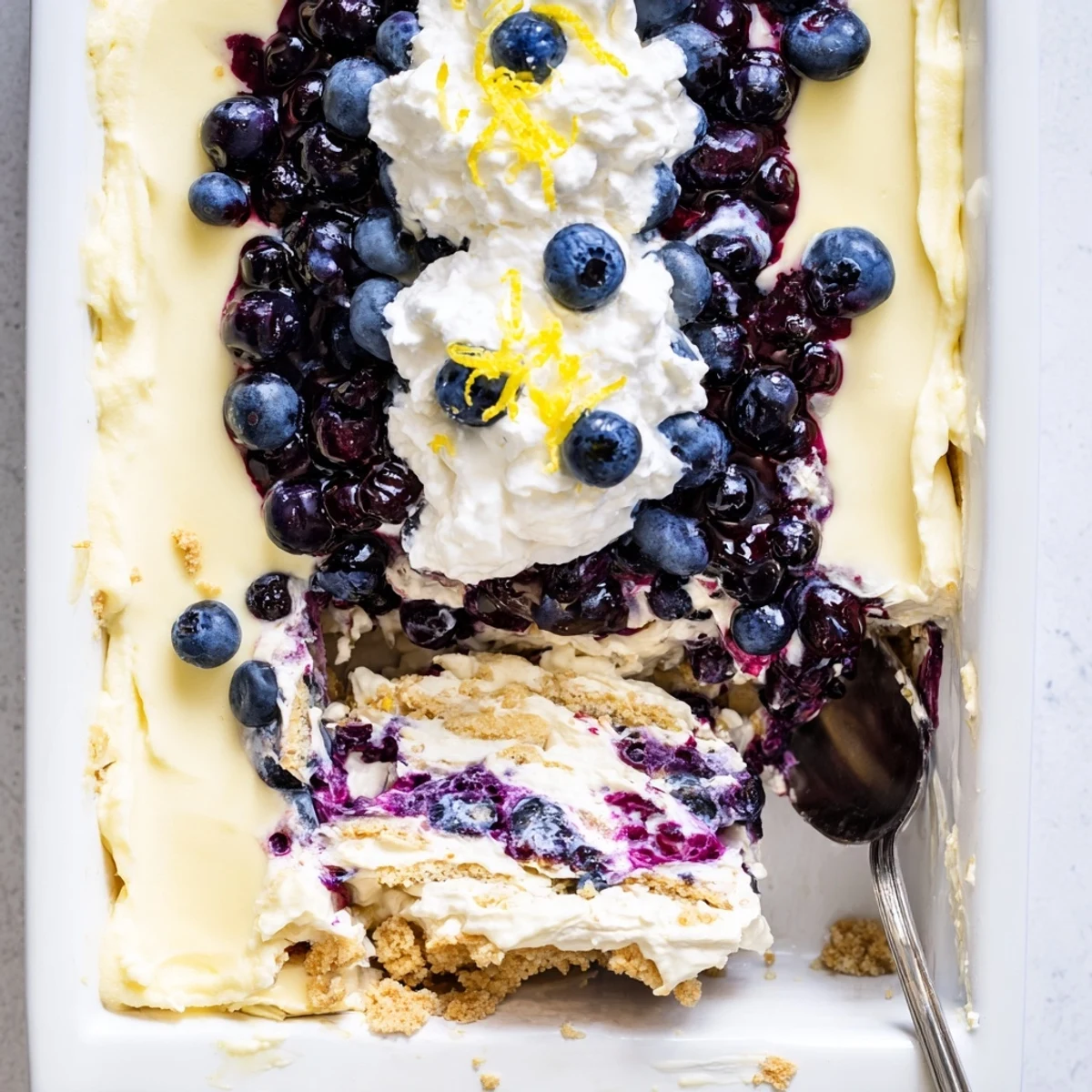 A square of lemon blueberry lasagna dessert with creamy filling and purple sauce