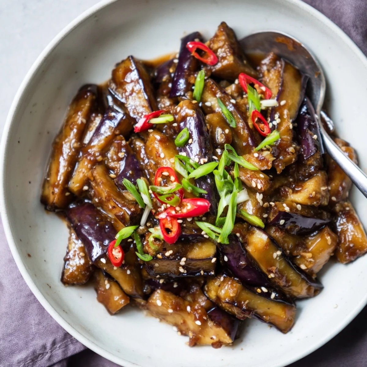 Gently sauced Sichuan Style Braised Aubergines garnished with scallions and sesame oil