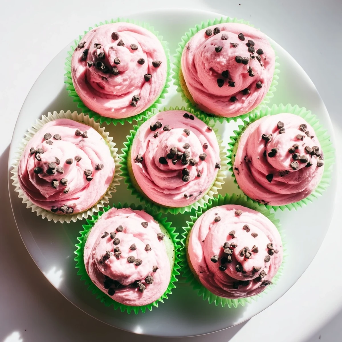 Freshly baked watermelon cupcakes with swirls of pink watermelon buttercream frosting and seed details