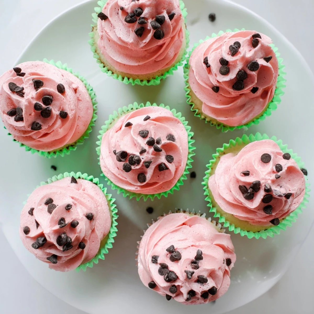 Moist vanilla watermelon cupcakes decorated with creamy pink frosting and chocolate sprinkles