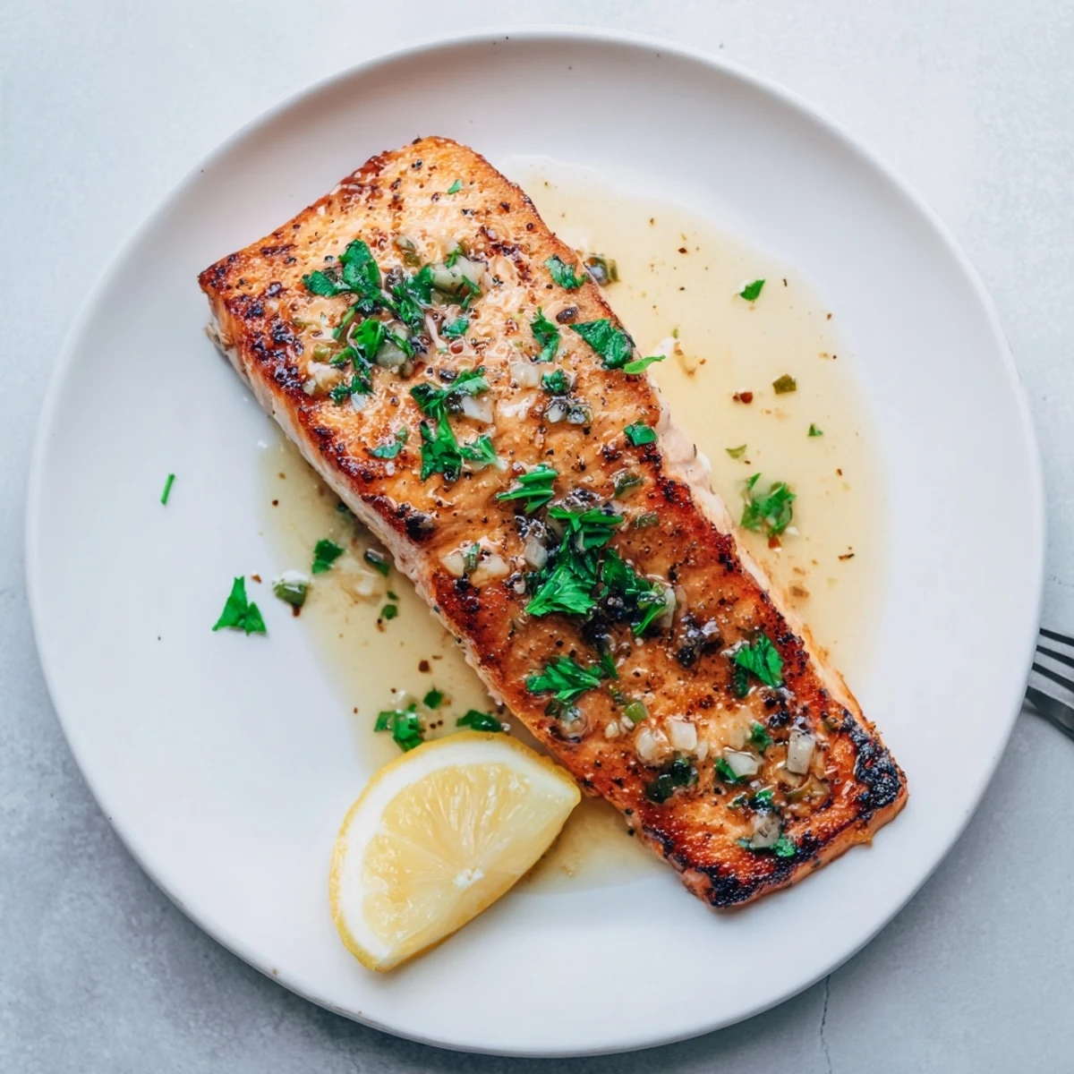 Restaurant-worthy pan seared salmon topped with aromatic garlic butter and fresh parsley garnish