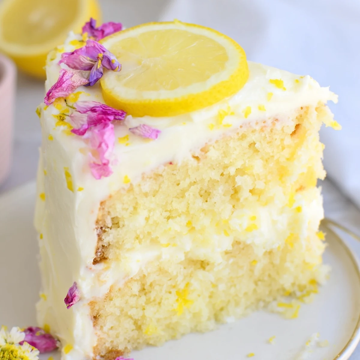 Golden lemon birthday cake layers stacked with creamy tangy frosting and fresh lemon garnish