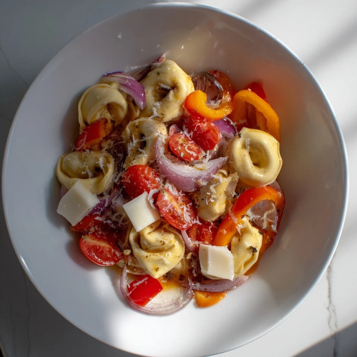 Colorful fresh grinder tortellini salad bowl loaded with vegetables, provolone, and zesty Italian dressing