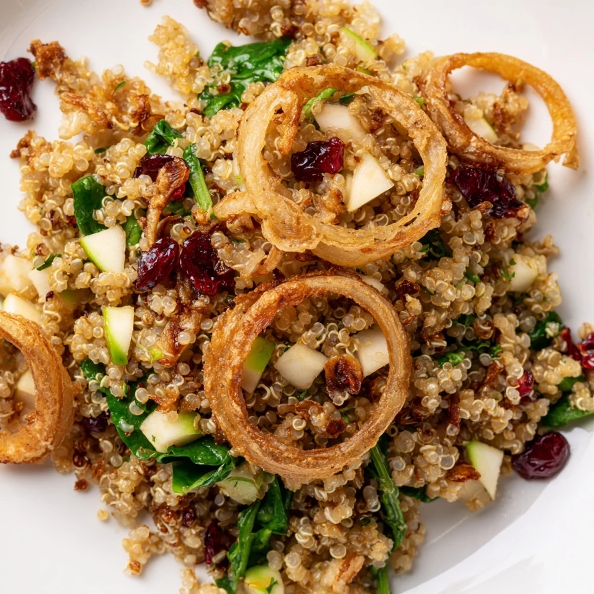 Golden crispy shallots crown a colorful honey mustard quinoa apple salad in a rustic bowl