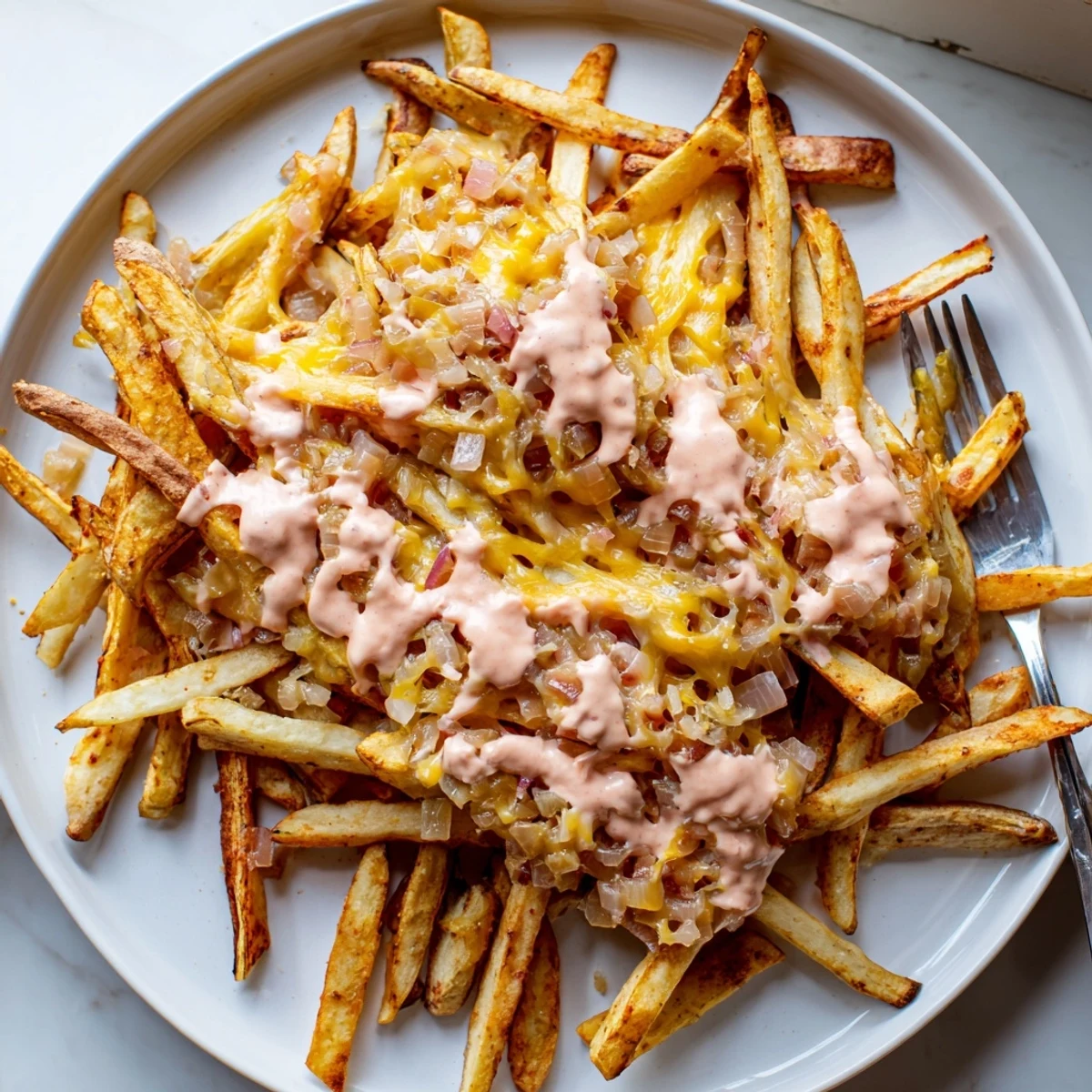 Steaming pile of Animal Style Fries drizzled with creamy sauce and sprinkled with melty cheese